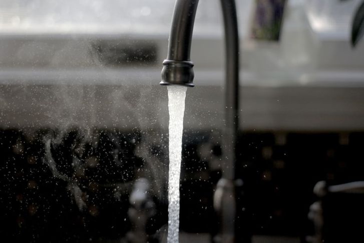 A black and white shot of a faucet running water